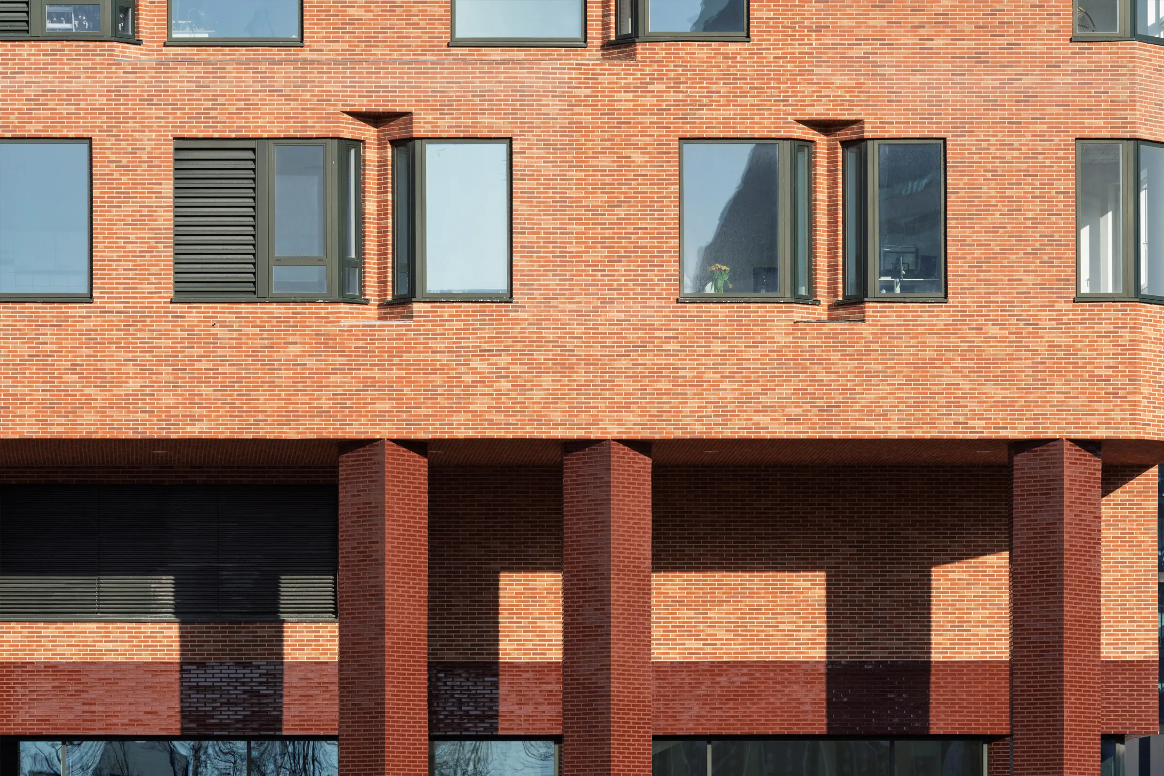 Detail fasády ukazuje práci s hloubkou, stínem a cihlovým povrchem.