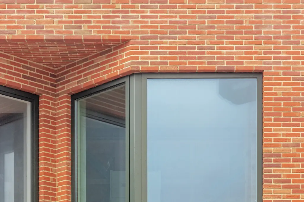 Detail cihlové fasády obytné věže projektu De Puls s plasticky tvarovanými arkýři.