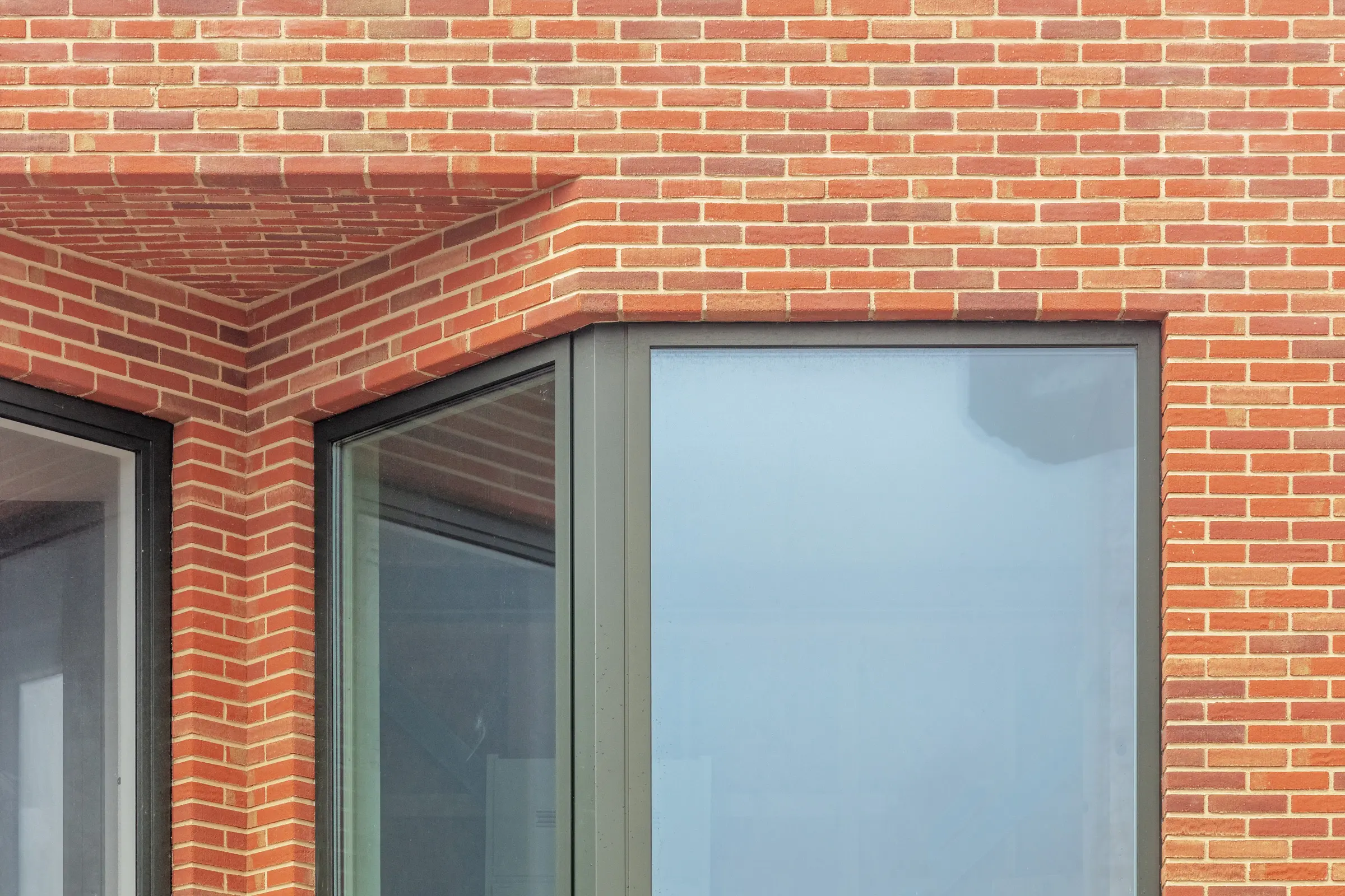 Detail cihlové fasády obytné věže projektu De Puls s plasticky tvarovanými arkýři.