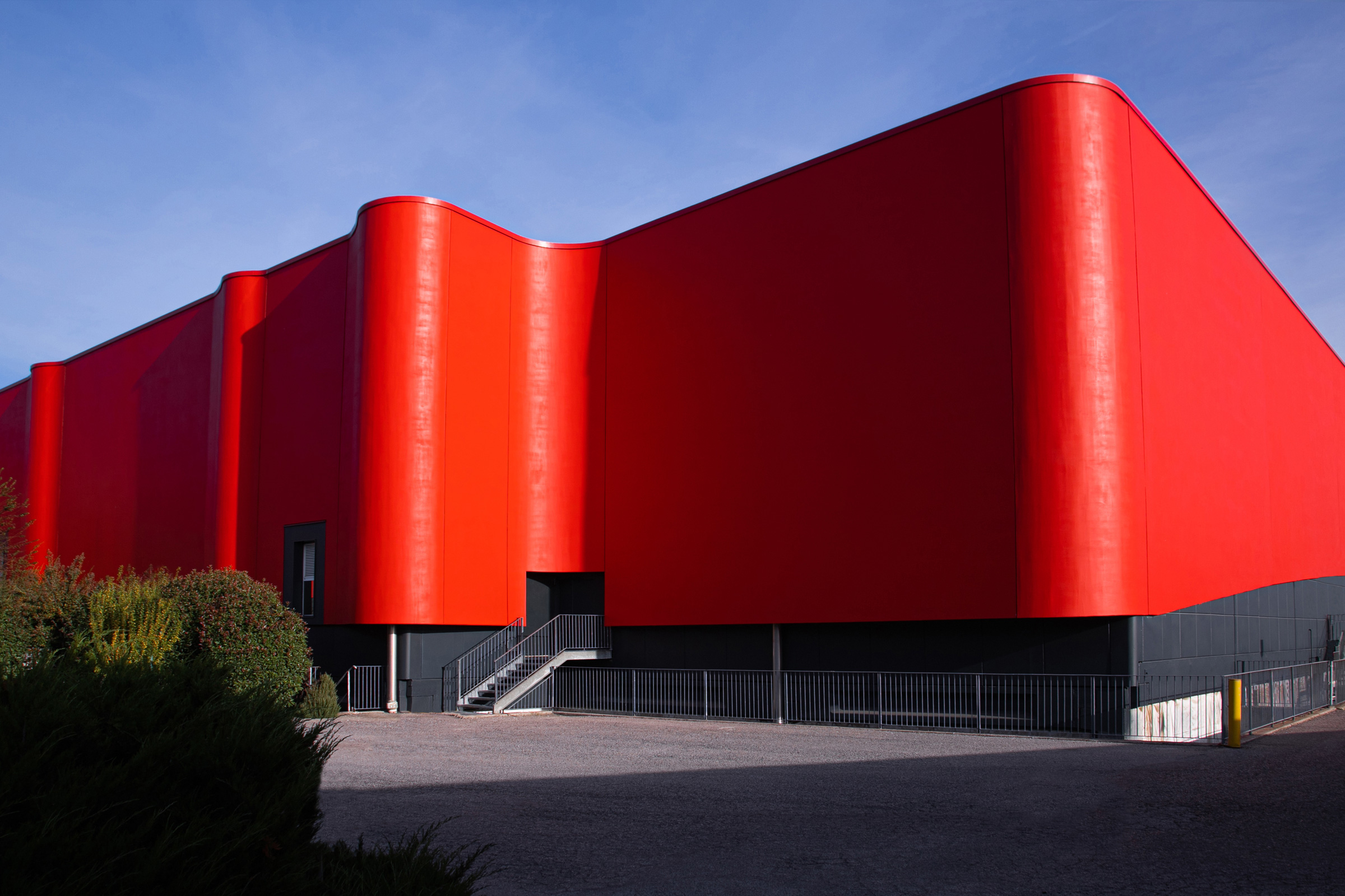 Budova s ​​ikonickou červenou stuhou a odrazem na hladině jezírka.